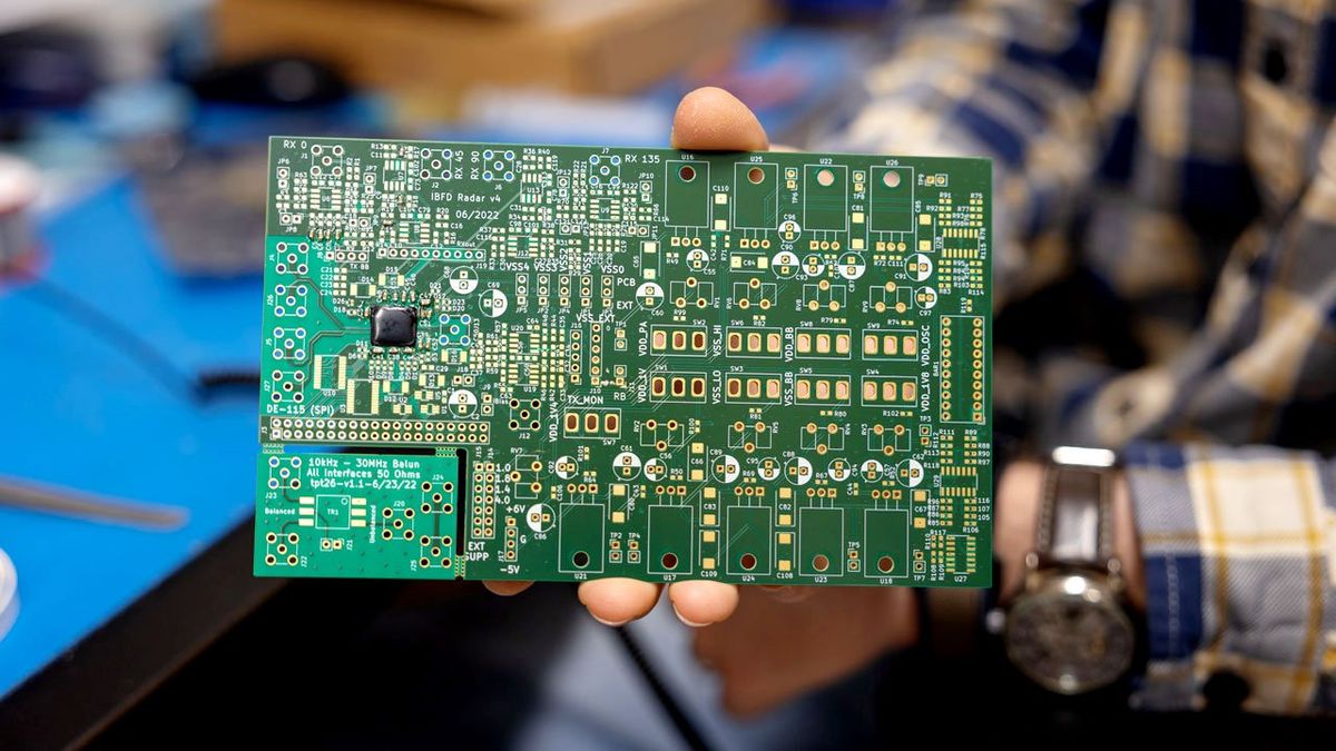 hand holding a green and gold computer board in their hand