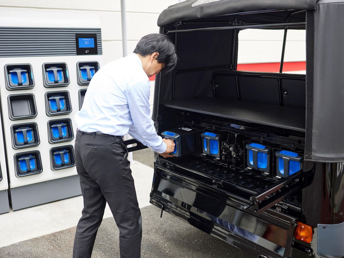 ​Honda researcher inserts a charged Mobile Power Pack e-battery into an e-rickshaw.