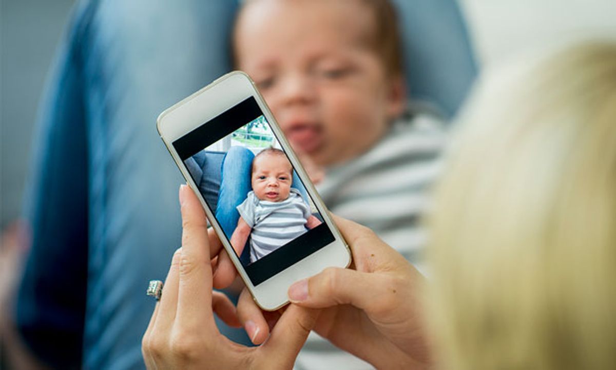 Image of a parent taking a photo of their baby via smartphone.