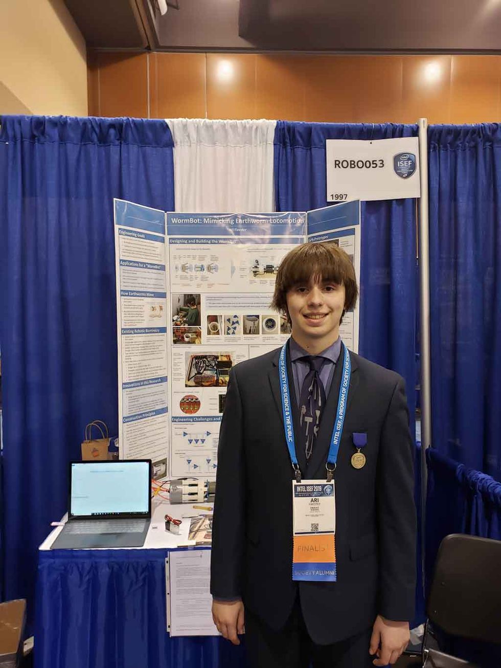 Image of Ari Firester standing in front of his project display. 