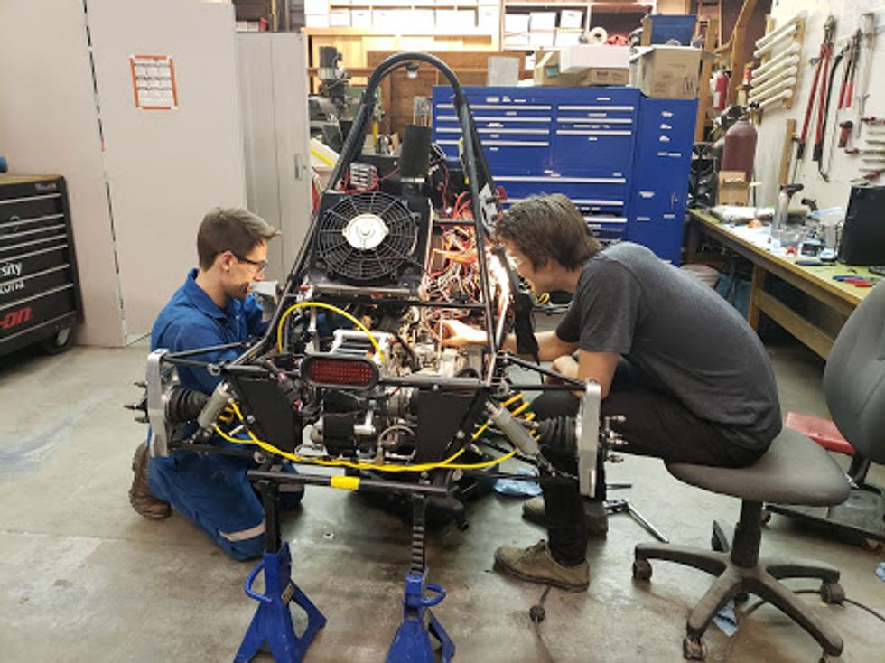 Image of Devin Fitzsimmons and Jules Pare checking the car's engine. 