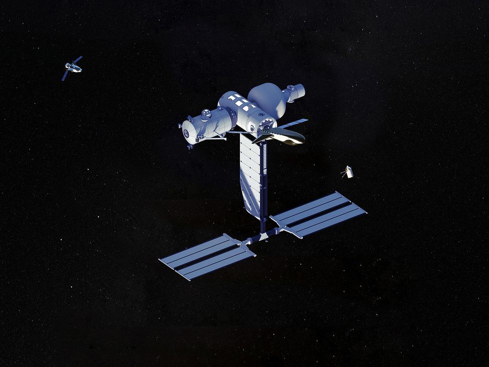 Image of space station against the back blackdrop of space. A crew module approaches the station from the left, while a central cylinder is joined by a perpendicular cylinder and an inflated spheroid on the far side.