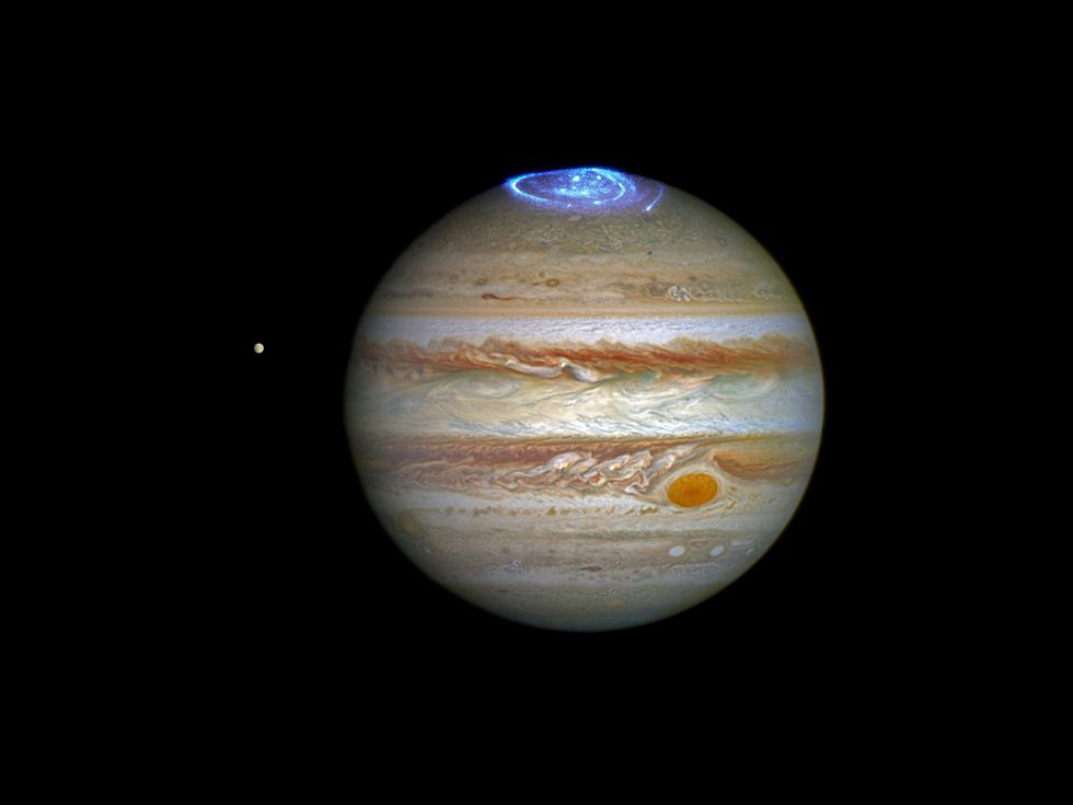 Image of the planet Jupiter with a photograph of an aurora at the planet's north pole in glowing blue light