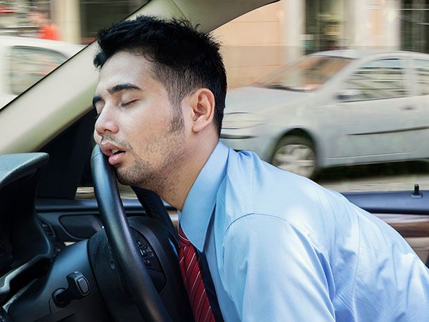man napping with head against steering wheel