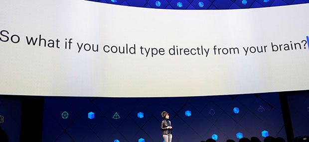 A woman stands on stage at Facebook's developer conference. Behind her a giant screen displays the text: “So what if you could type directly from your brain?”