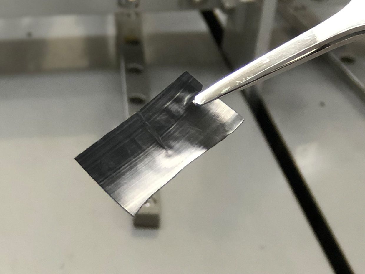 Photograph of a sheet of pure carbon, multi-walled perpendicular nanotubes, held by a pair of tweezers.