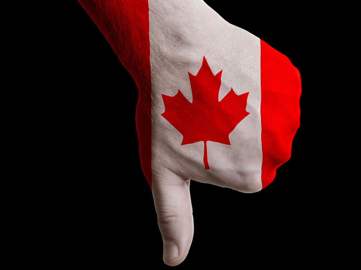 Photograph of someone giving a thumbs down, with the Canadian flag painted on their hand.