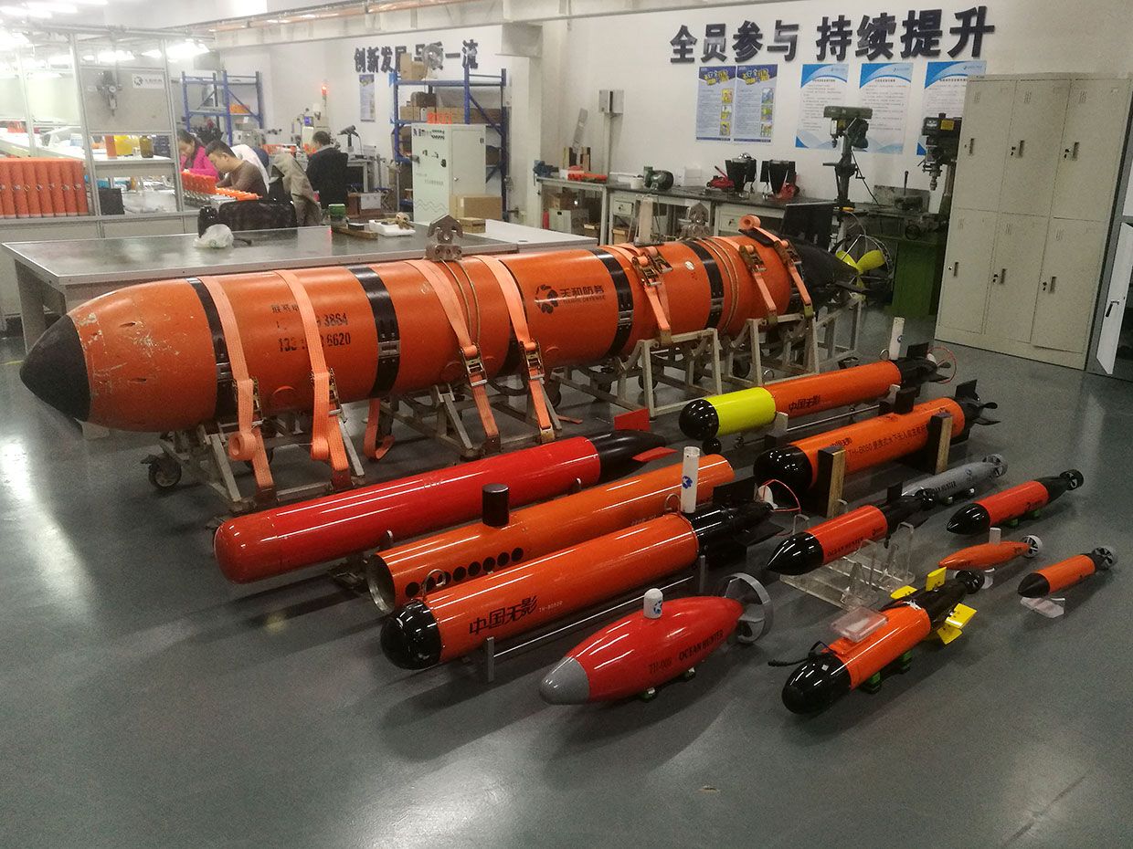 A photo of cylindrical orange AUVs stacked up in a room.