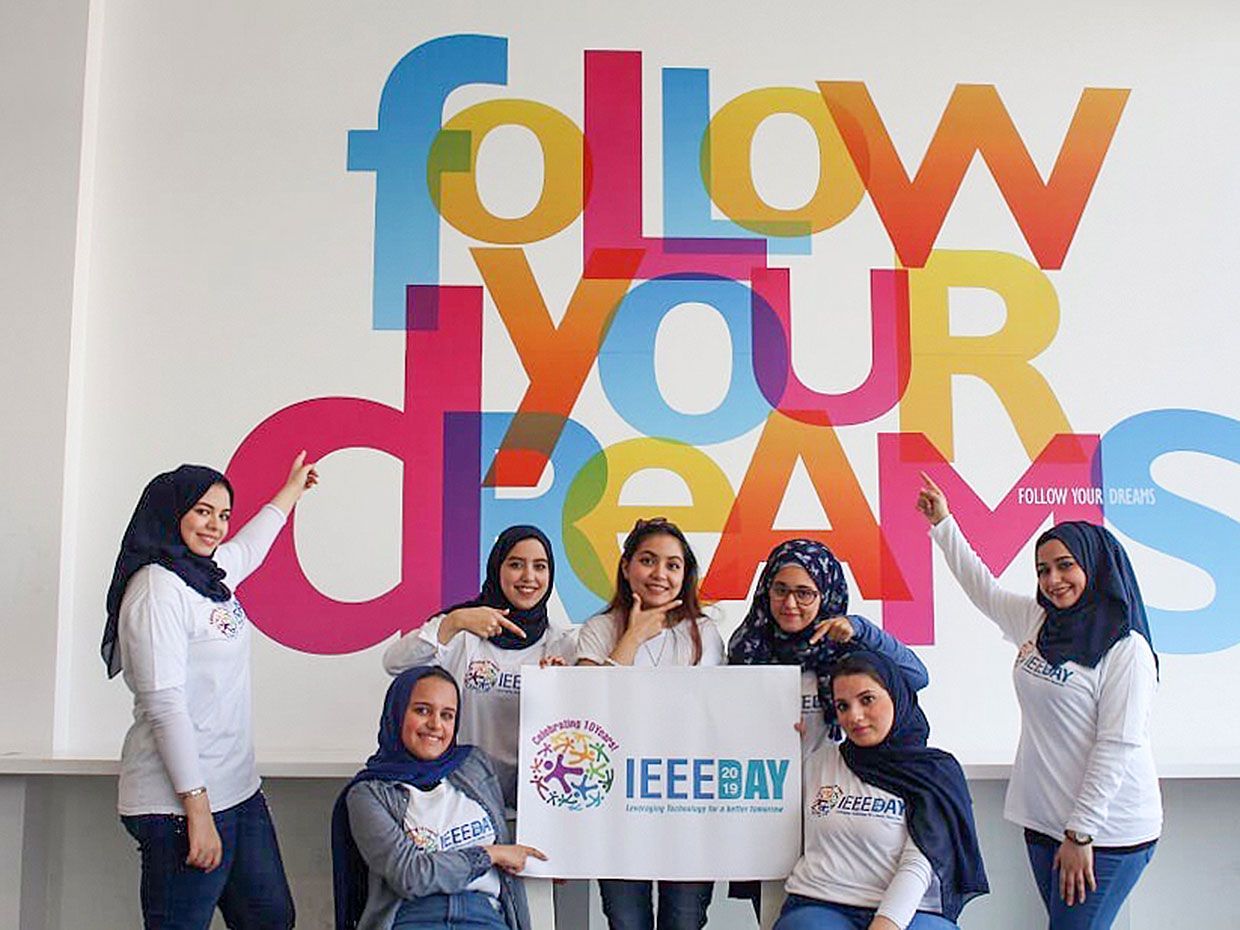 Photograph of members of the Ajman University Student Branch - UAE in front of a sign that says follow your dreams.