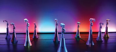 Ten colorfully lit robot arms on metal pedestals spread out across a dance stage