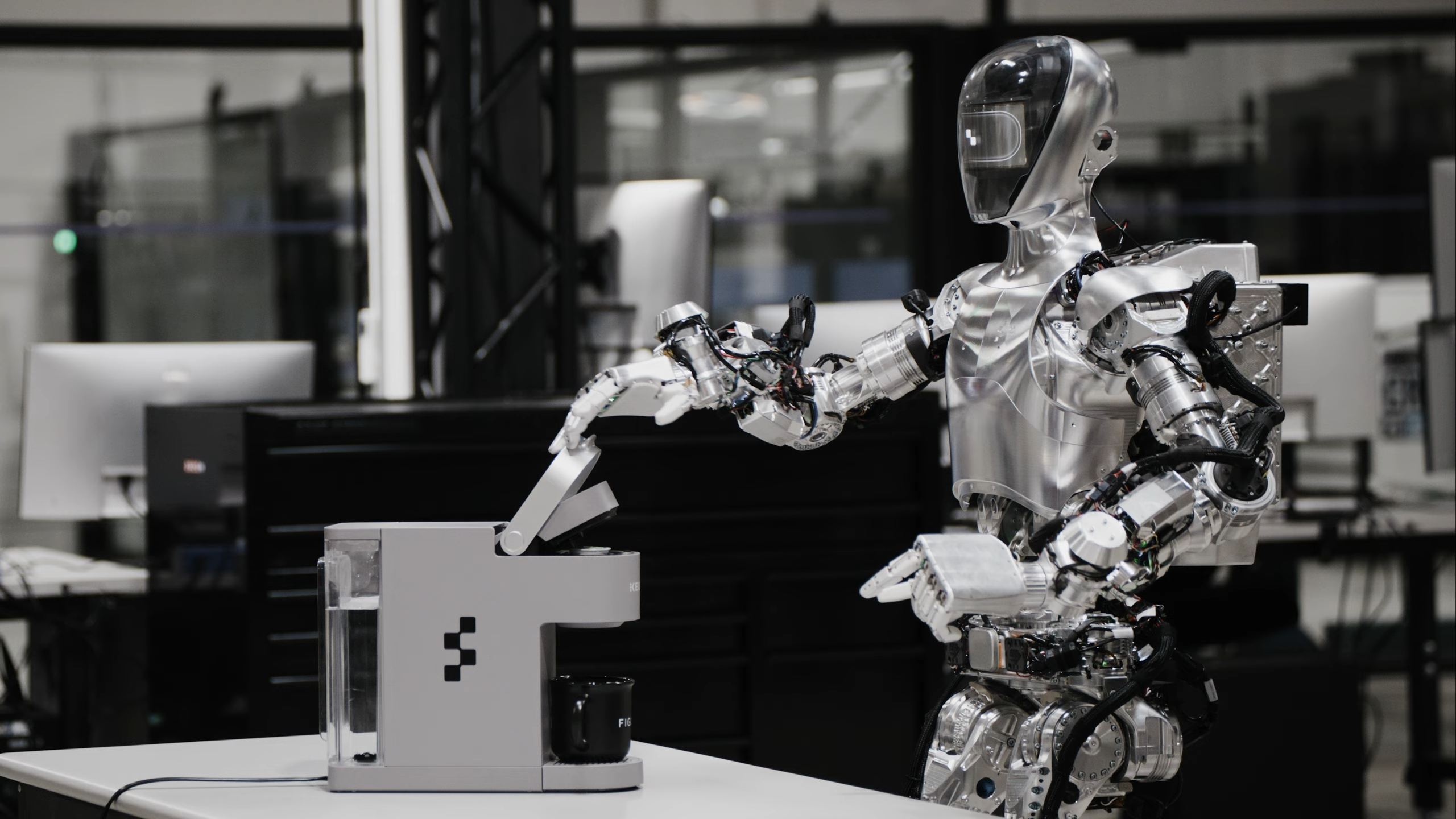 A photograph of a silvery humanoid robot placing a pod into a Keurig machine.