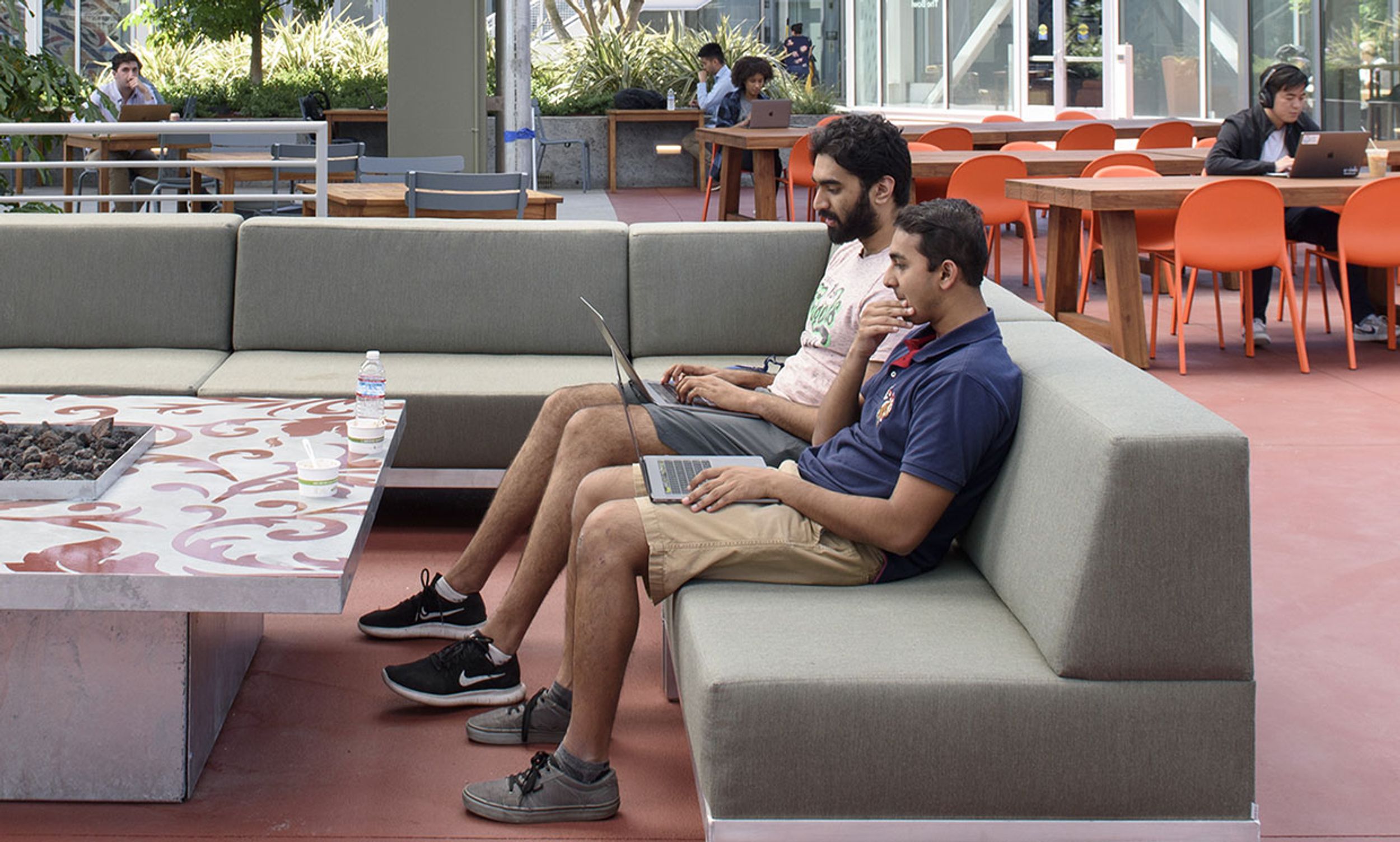In this 2018 photo, Facebook employees work on laptop computers in an outdoor space at their MPK 21 office building in Menlo Park, California.