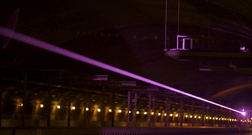 In this image, a narrow purple beam shines across a darkened room.
