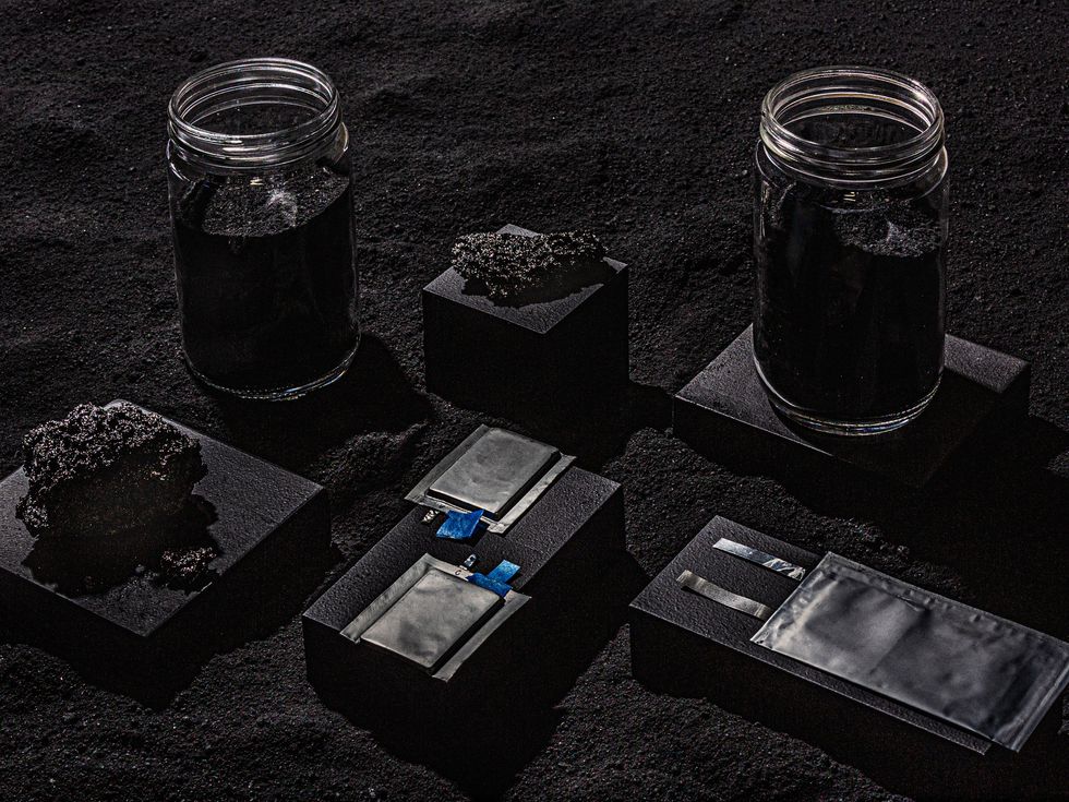 bocaux avec du sable noir, des roches poreuses et des boîtes de conteneurs noires posées sur du sable noir