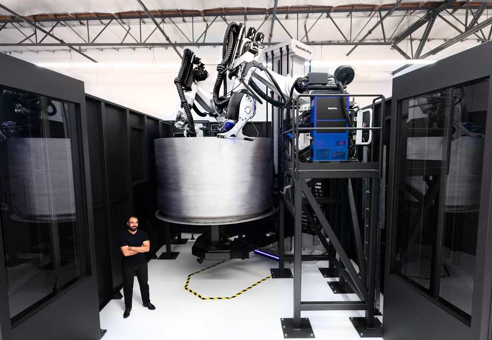 Jordan Noone, Relativity Space cofounder, stands in front of the company\u2019s newest 3D printer as it builds a fuel tank for the Terran 1 rocket.
