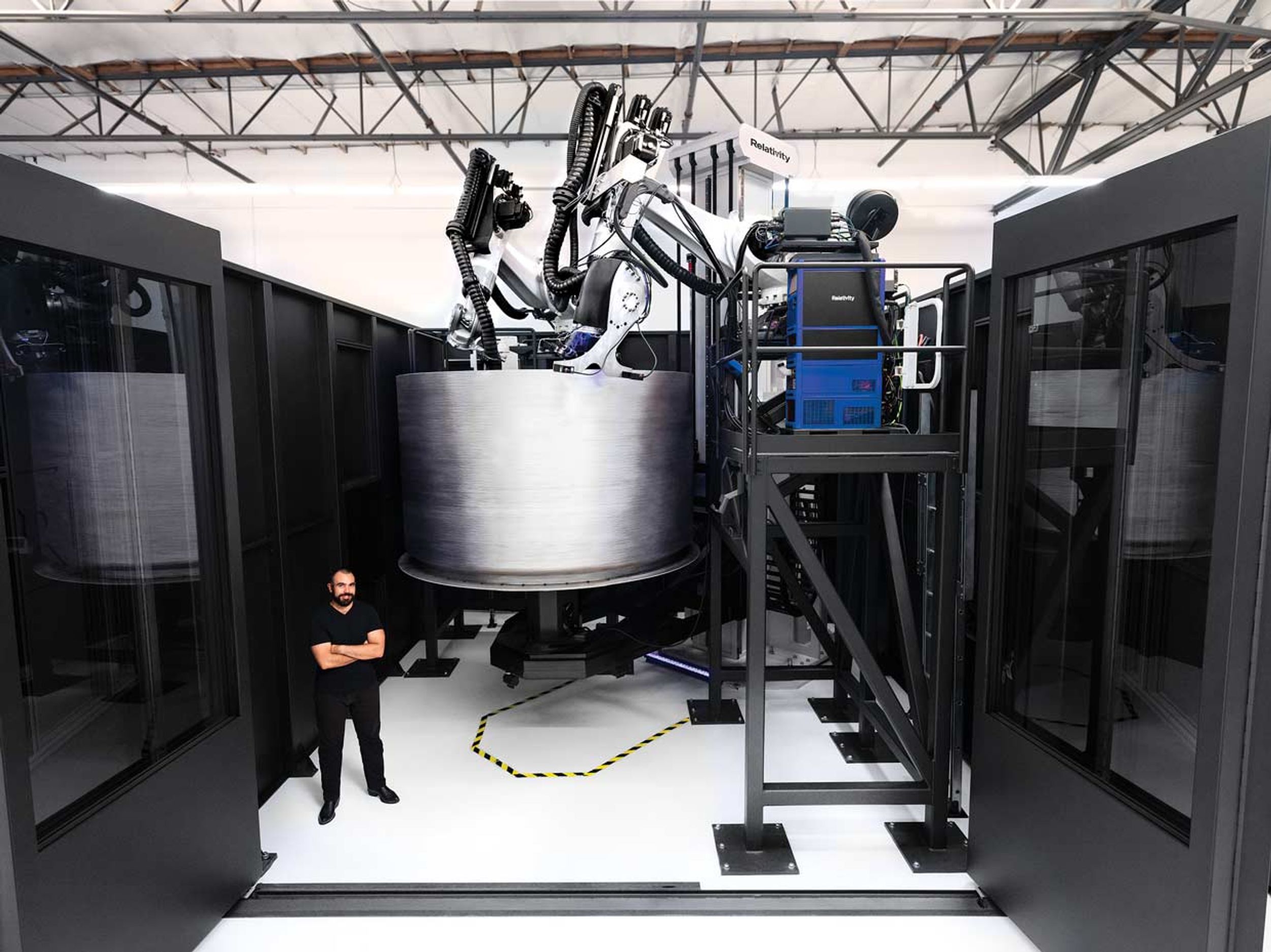 Jordan Noone, Relativity Space cofounder, stands in front of the company’s newest 3D printer as it builds a fuel tank for the Terran 1 rocket.