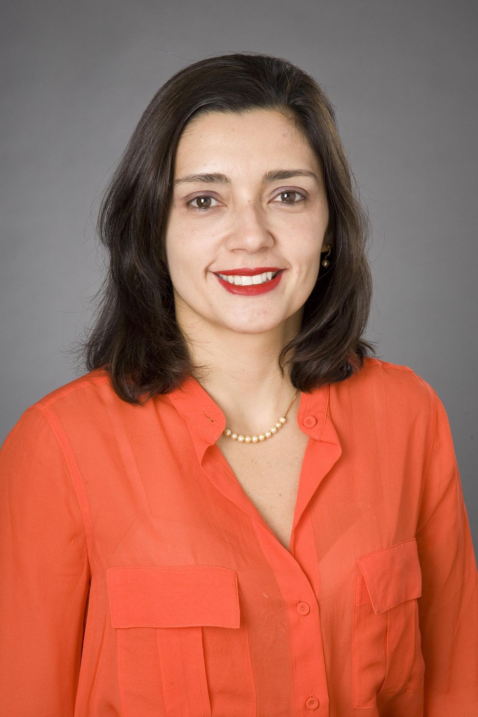 Juliana Freire smiles at camera posing against a gray background