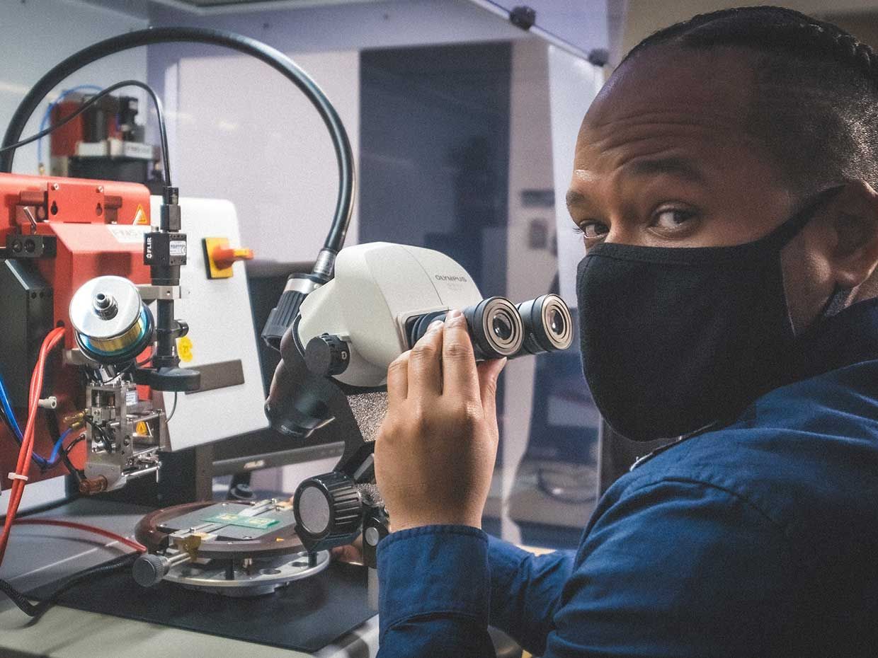 Image of Kenny Cardoso looking through photonics machinery.