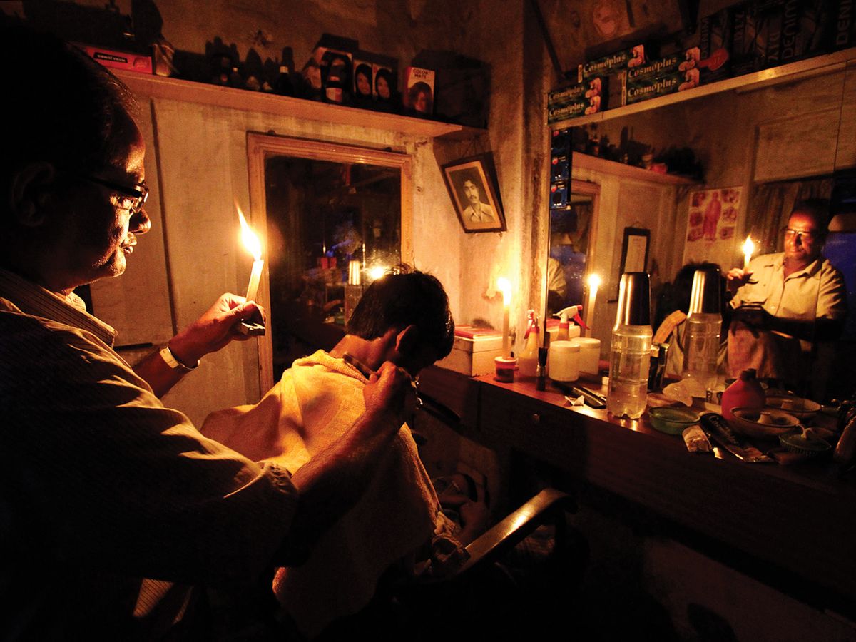 Kolkata cut: Life went on during the biggest blackout in history. This barber in the eastern city of Kolkata worked by candlelight.