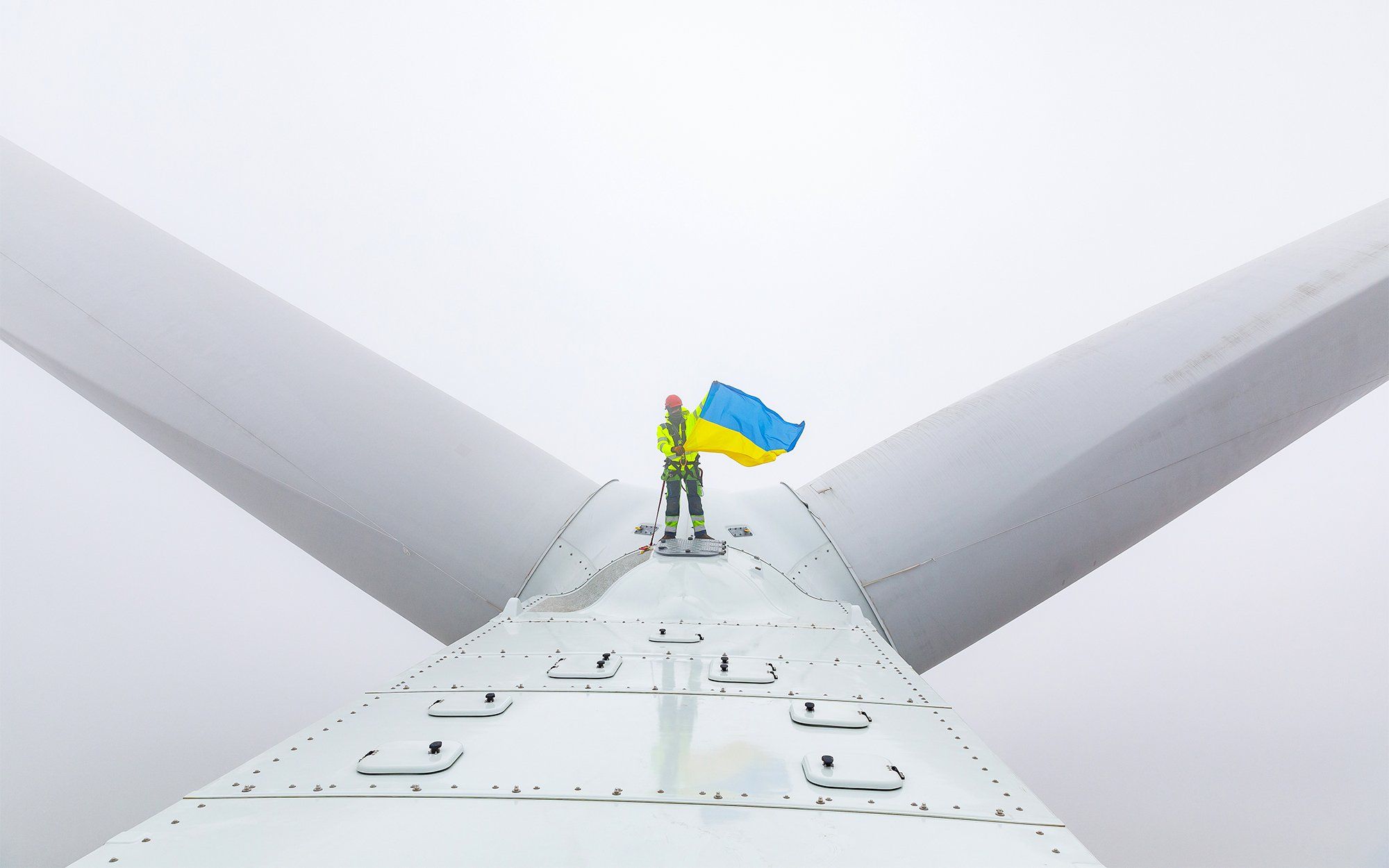 A worker holds a Ukrainian flag atop a wind turbine at the DTEK Renewables Tyligulska wind farm.