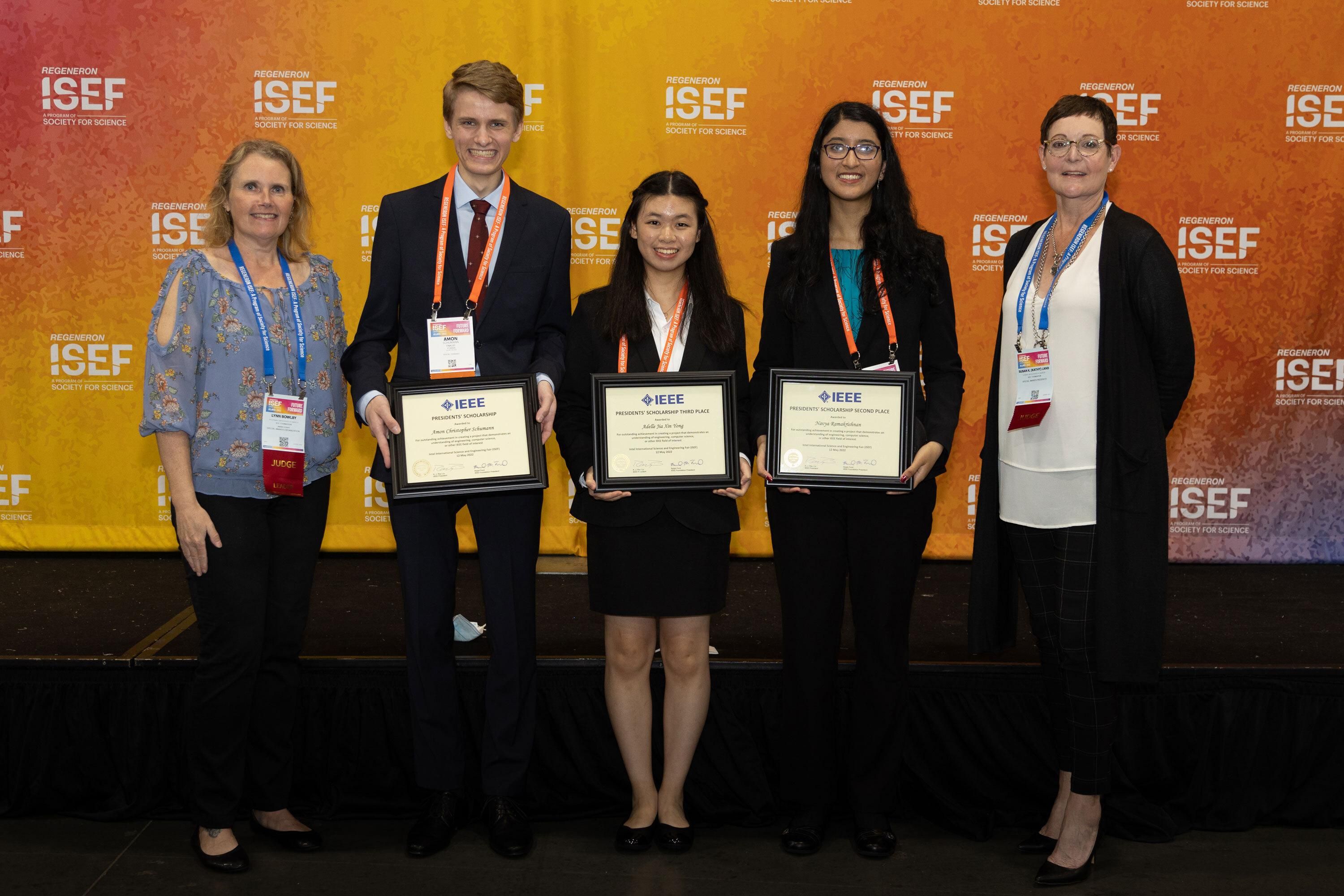 Four females and one male holding certificates are pictured in front of a banner that says ISEF.