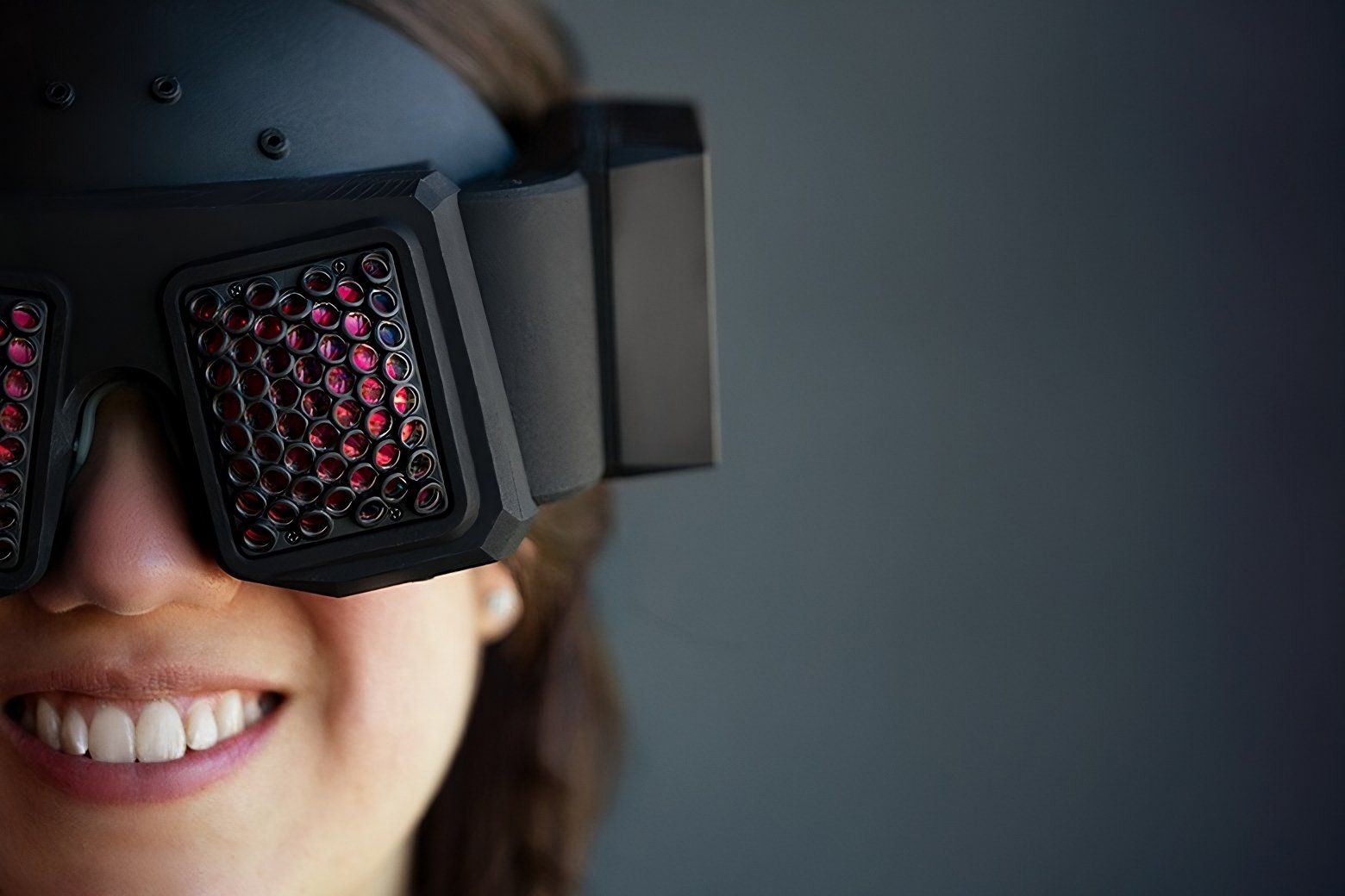 A photo of a woman wearing a black headset that has glowing red buglike lenses.