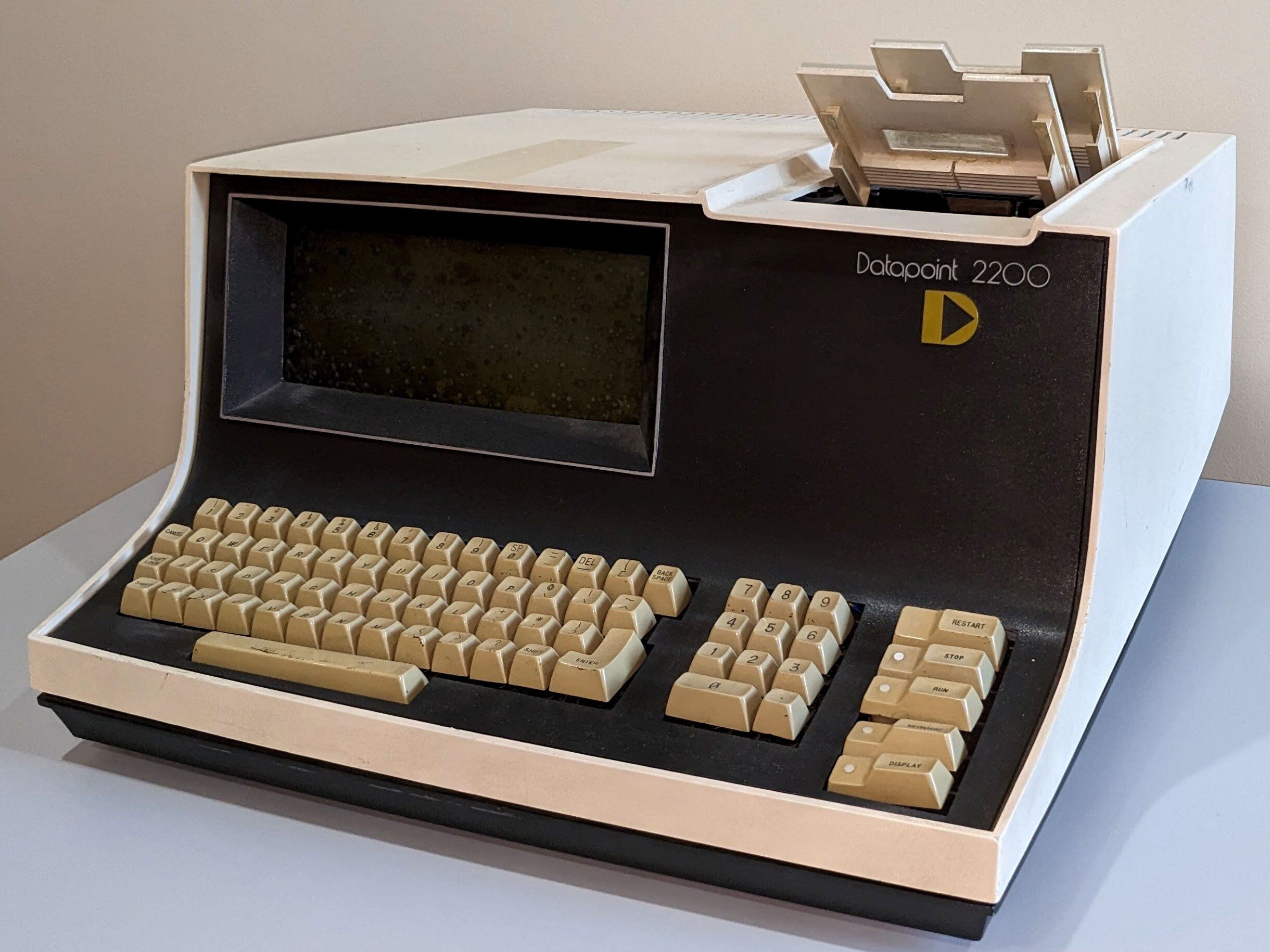 brown and beige box with curved end in front with a keyboard and screen and two pieces sticking out on top right side