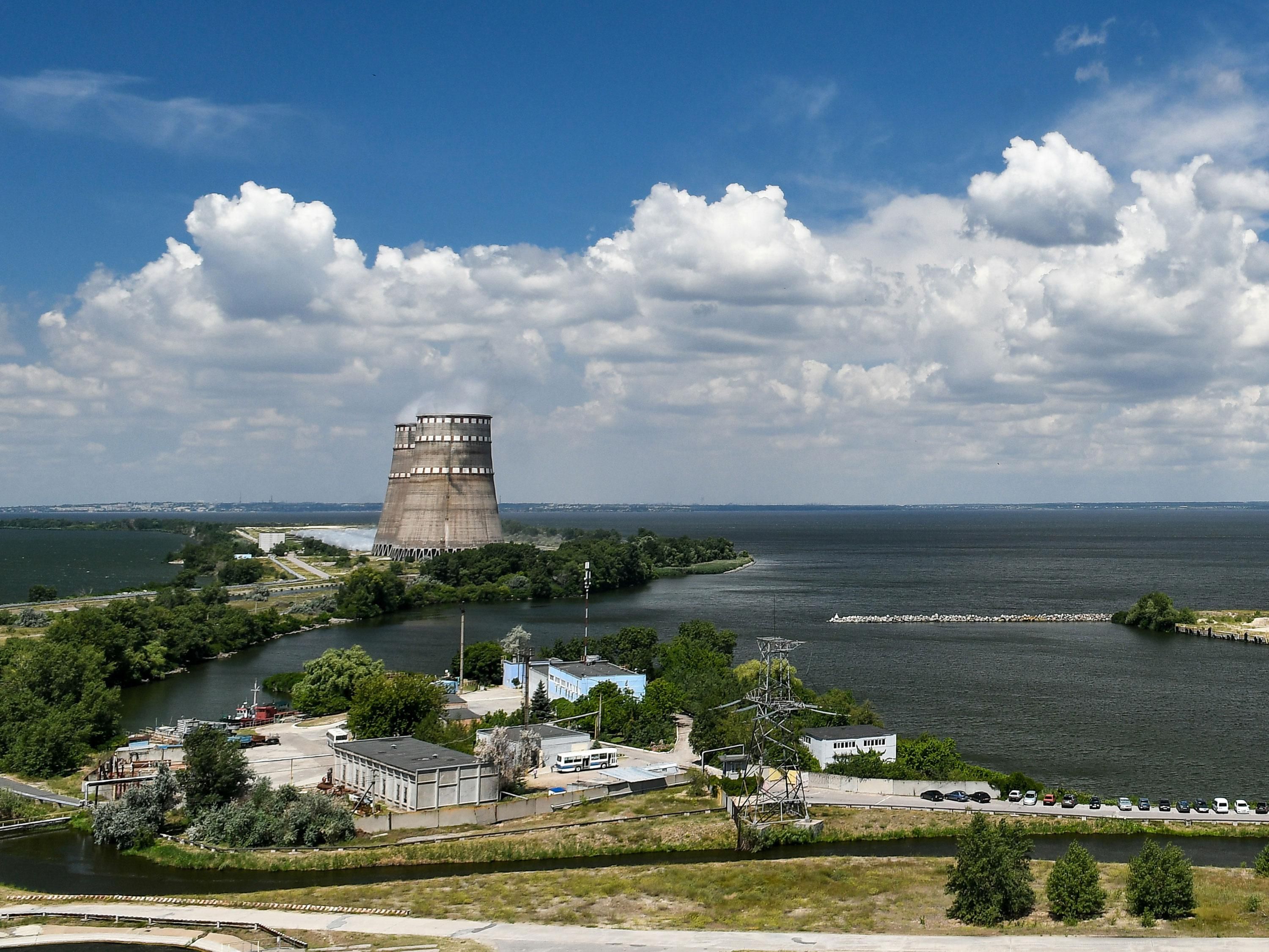 A nuclear power plant on the shore of a large body of water, with two tall conical towers in the middle of the facility