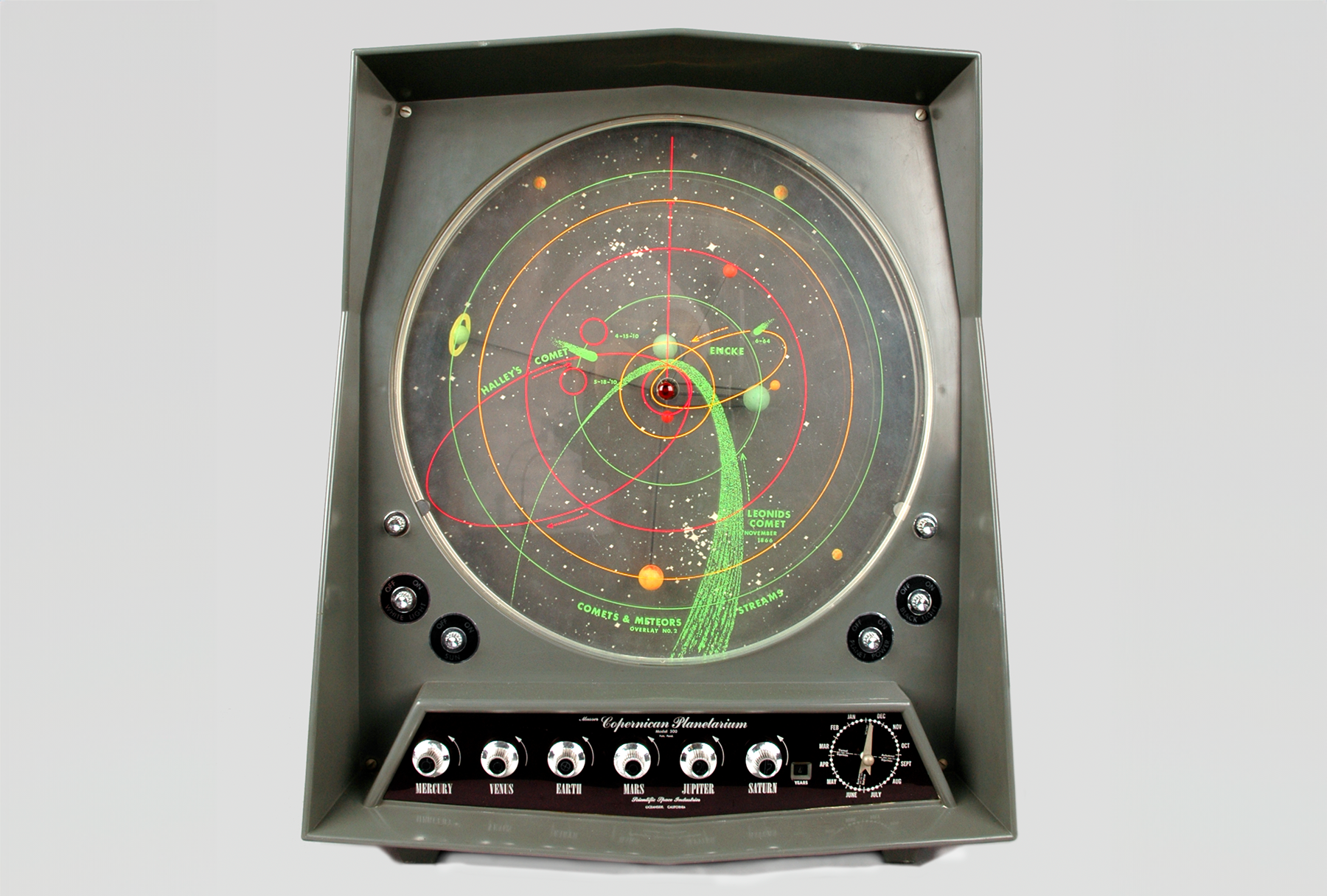 A color photo of an electronic device with knobs across the bottom and a round display depicting the solar system.