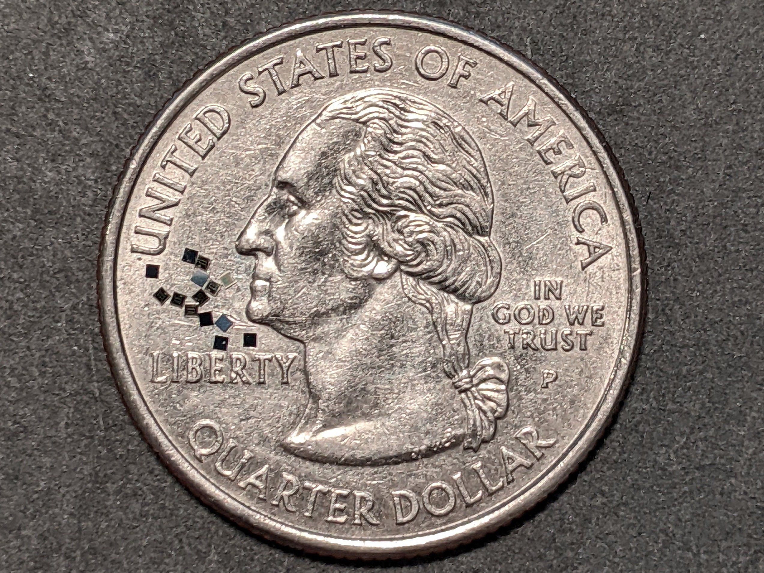 little black squares on top of a silver quarter coin
