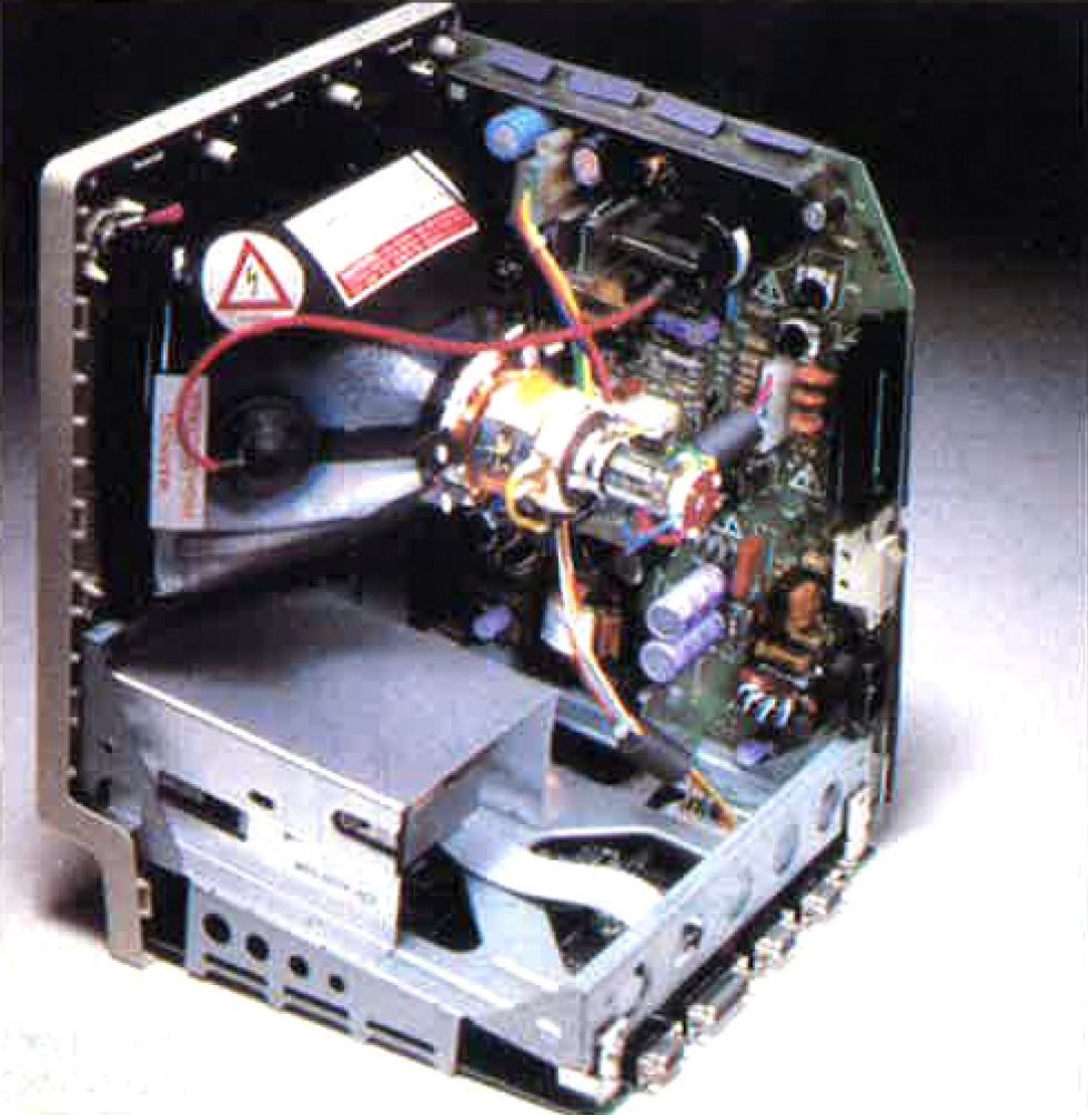 Looking into the open back of a computer, with metal enclosures and wires, and the back of a cathode ray tube.