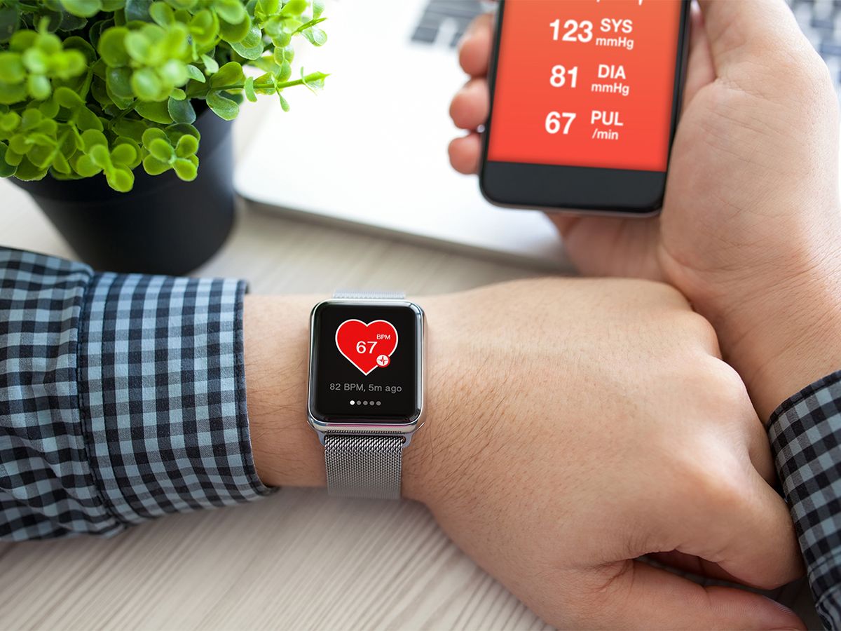 Man checking heart rate on smartwatch with app open on his phon