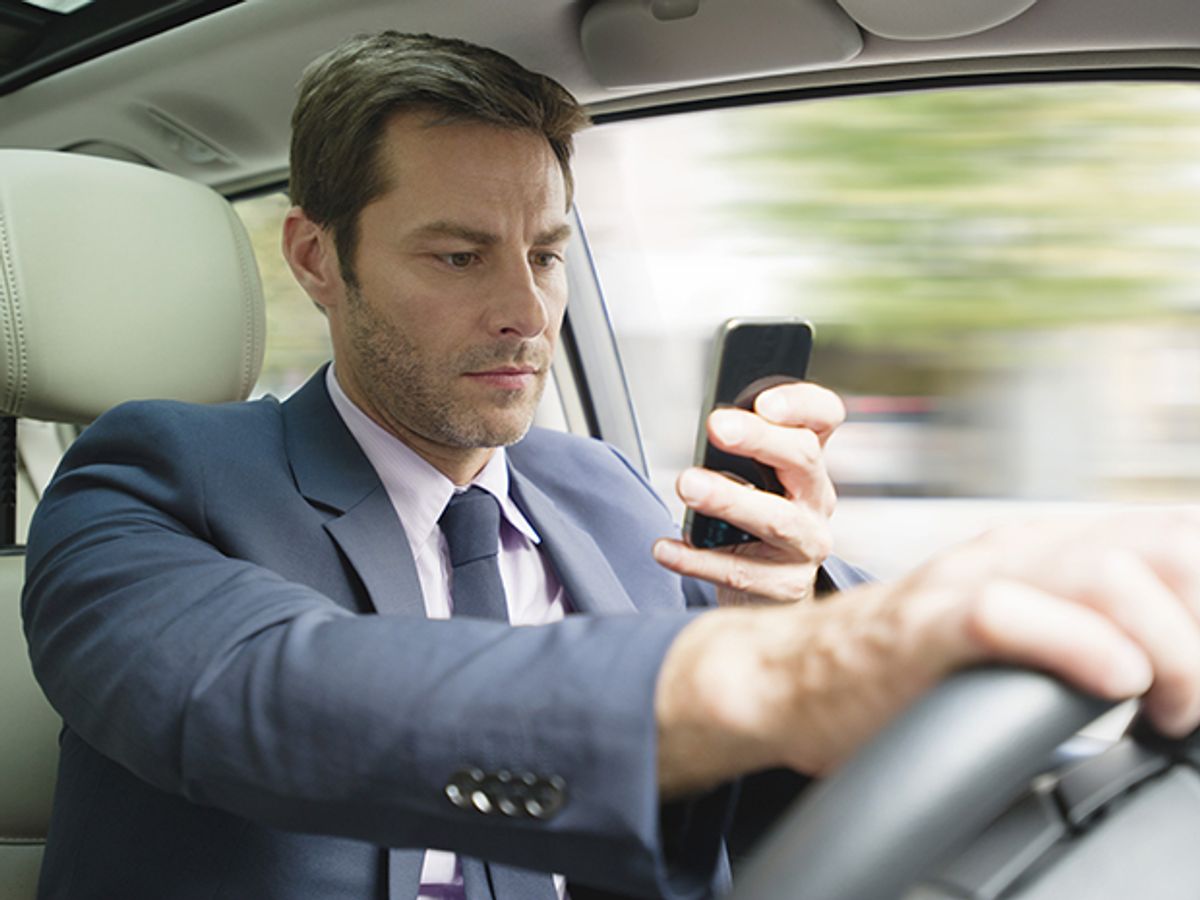 Man driving and looking at smartphone