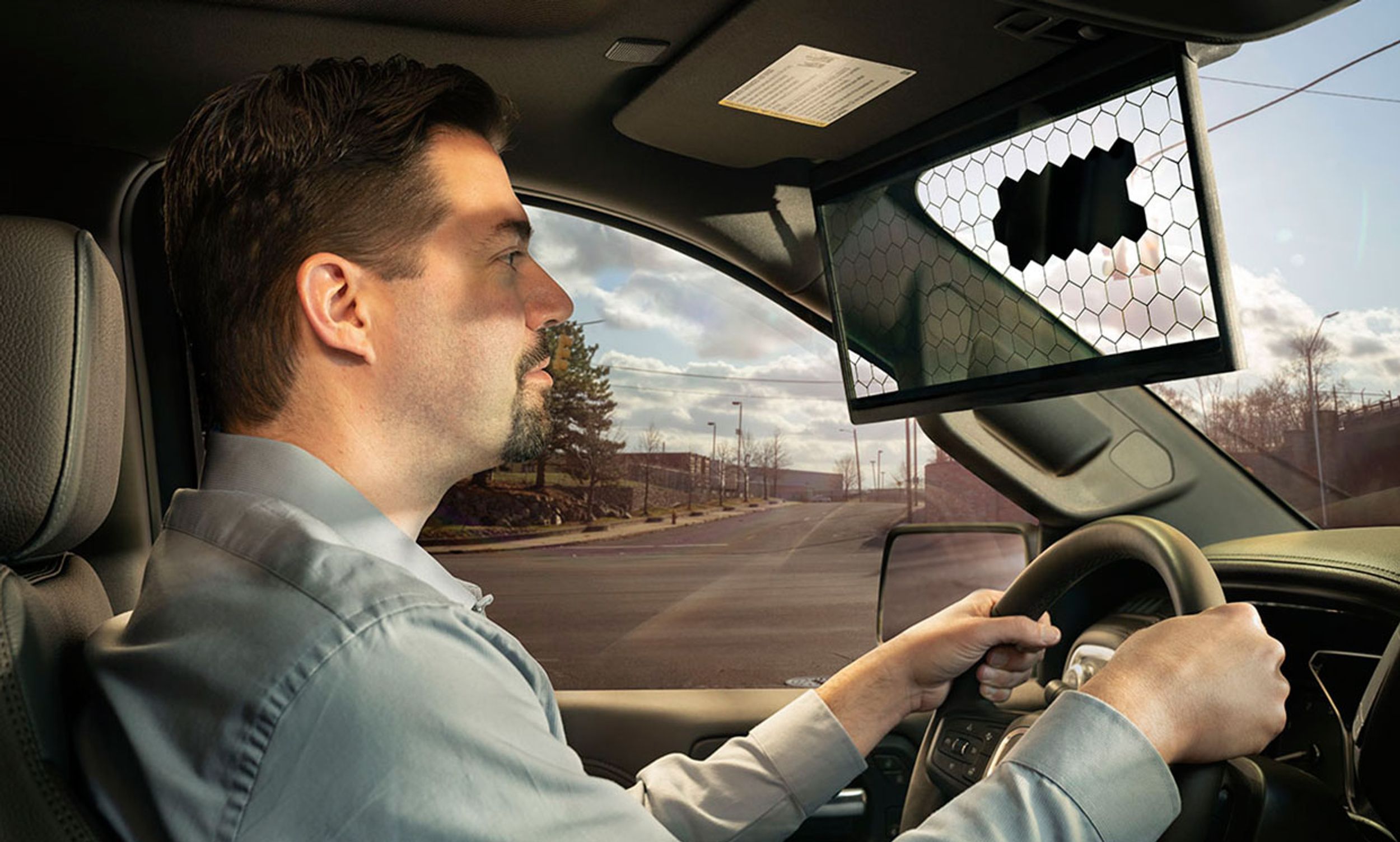 Man in a car drives into the sun while the Bosch Virtual Visor blocks a distinct patch of sun from its liquid crystal display (LCD) screen.