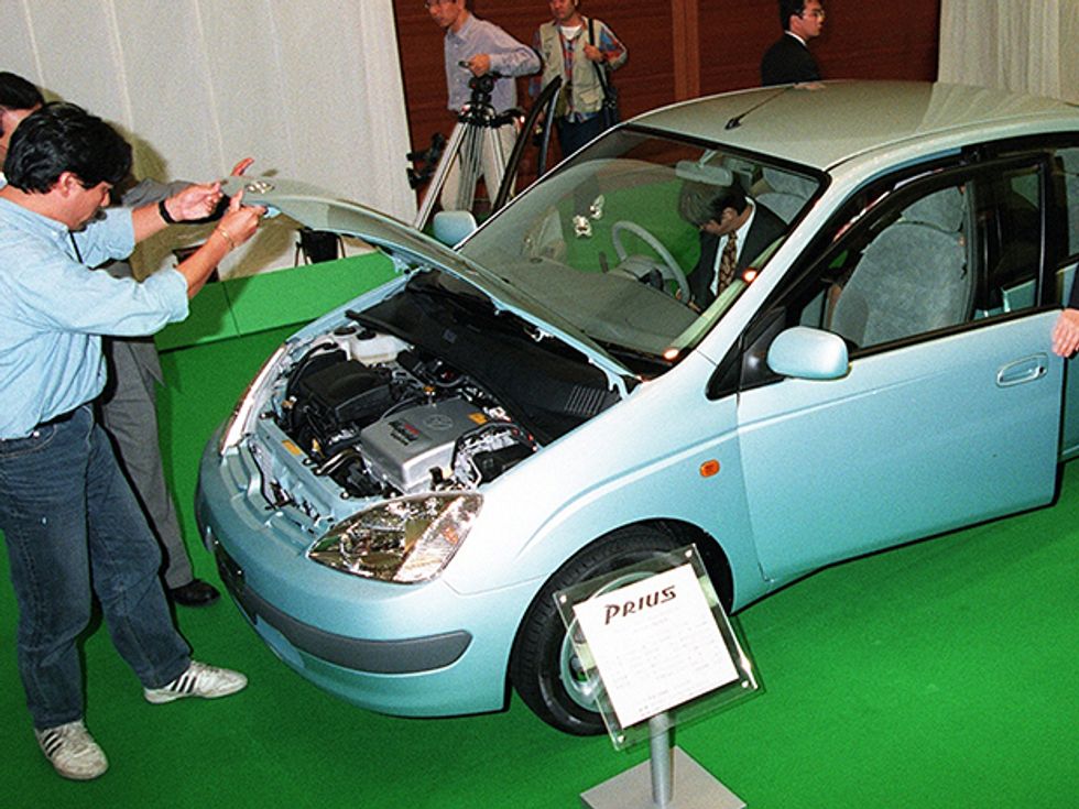 man inspects engine of 1997 Toyota Prius car