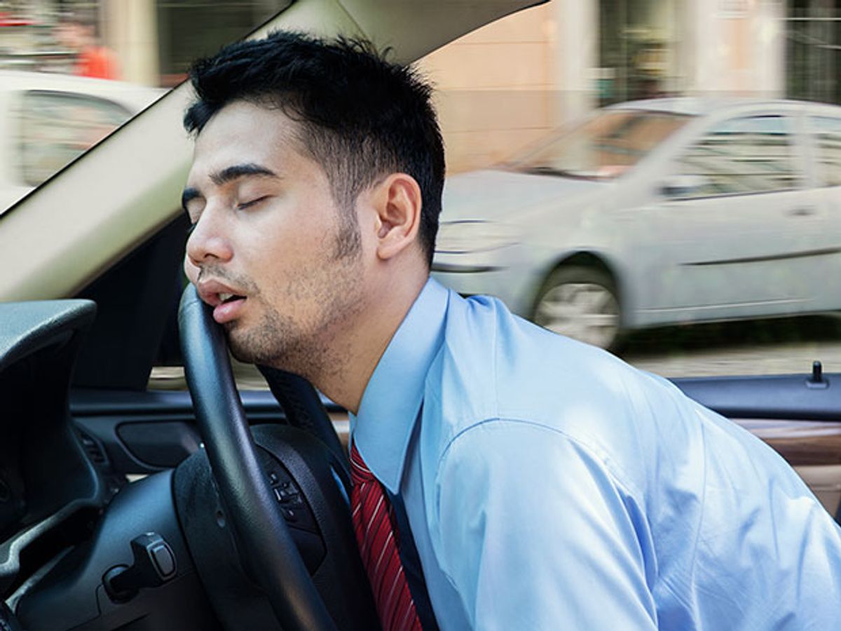 man napping with head against steering wheel