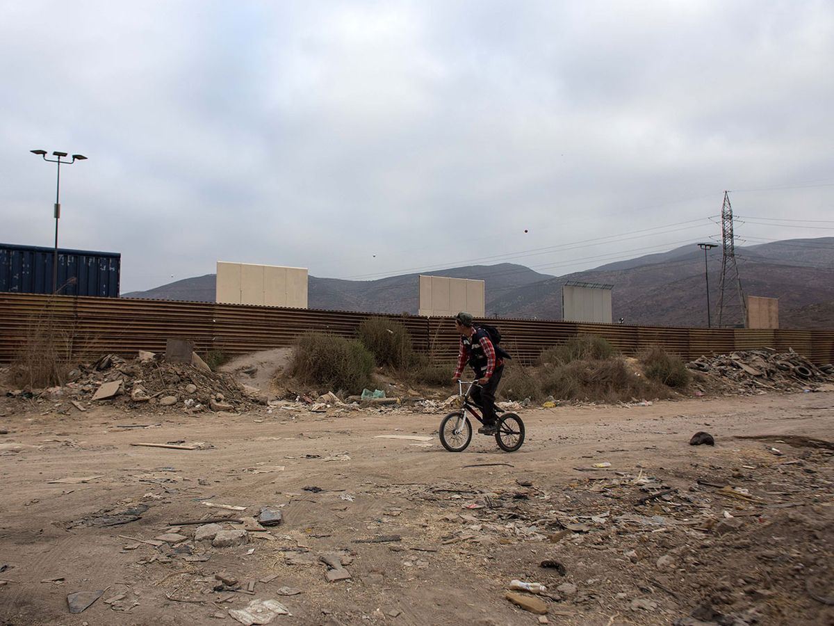 man on bmx bike on a dirt road by a border wall