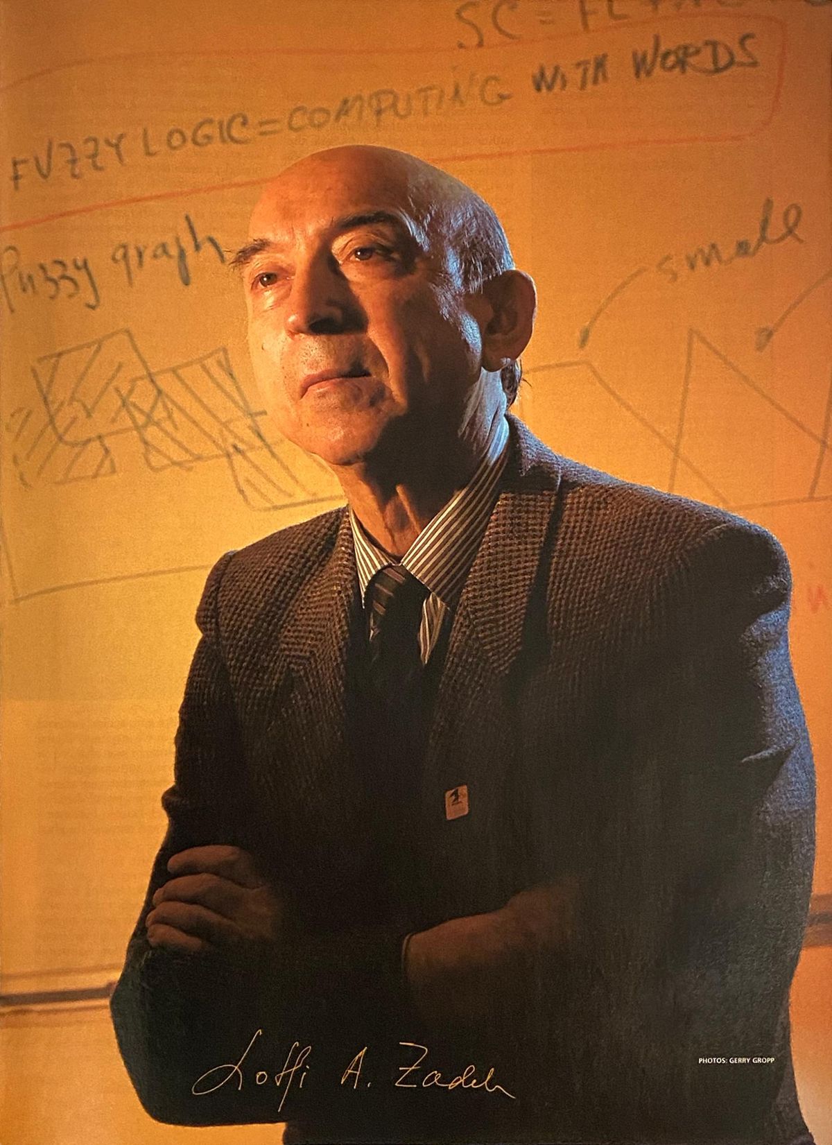 Man standing with arms crosssed in front of whiteboard, text visible reading fuzzy logic = computing with words, signed at bottom Lotfi A. Zadeh