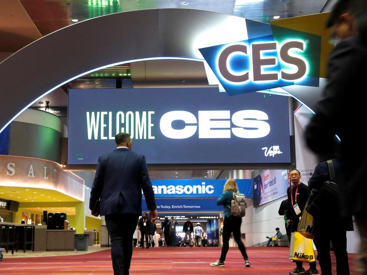 man walking through a convention center with a sign overhead that reads CES