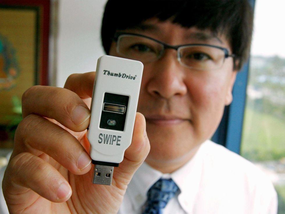 Man with white shirt, tie, and glasses holds thumb drive labeled SWIPE close to the camera