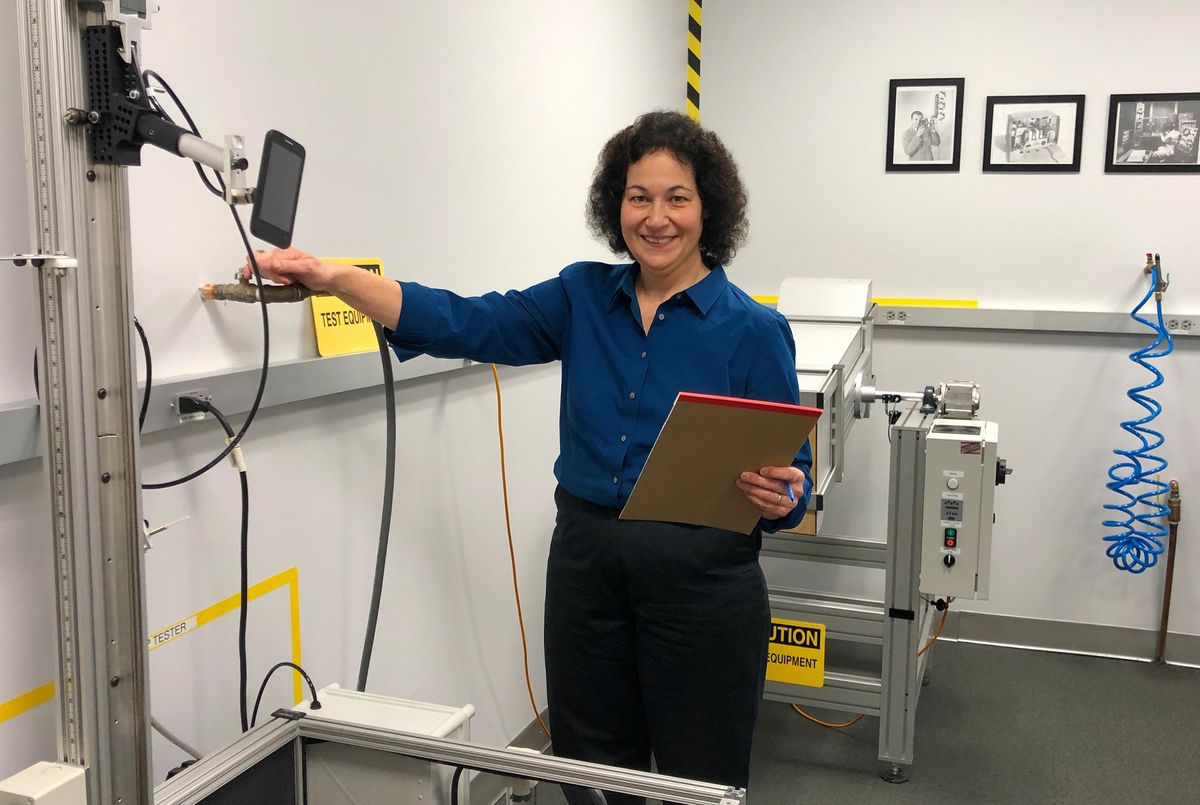 Maria Rerecich in the Consumer Reports labs in Yonkers, N.Y., with the phone drop tower (front) and tumbler (back) test equipment.