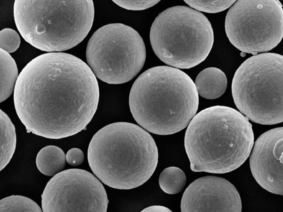 Microscope photo of metal grains showing gray spheres of different sizes grouped together.