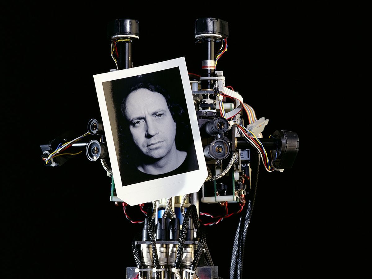 MIT humanoid robot Cog holding up a black and white portrait of Rodney Brooks