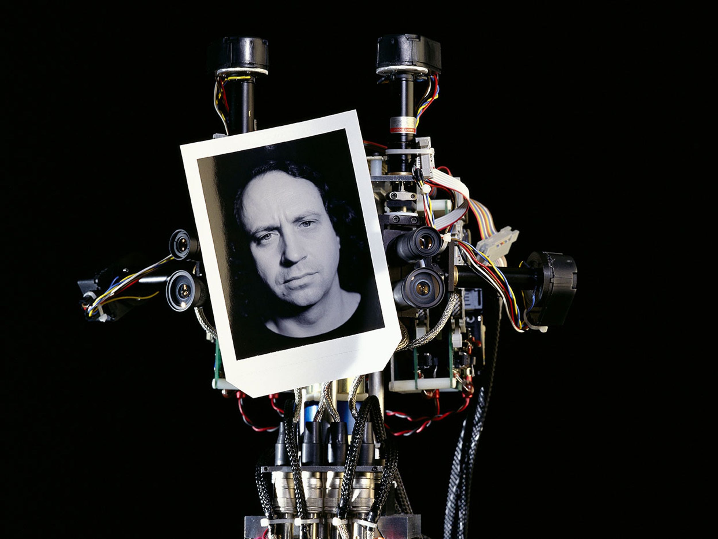 MIT humanoid robot Cog holding up a black and white portrait of Rodney Brooks