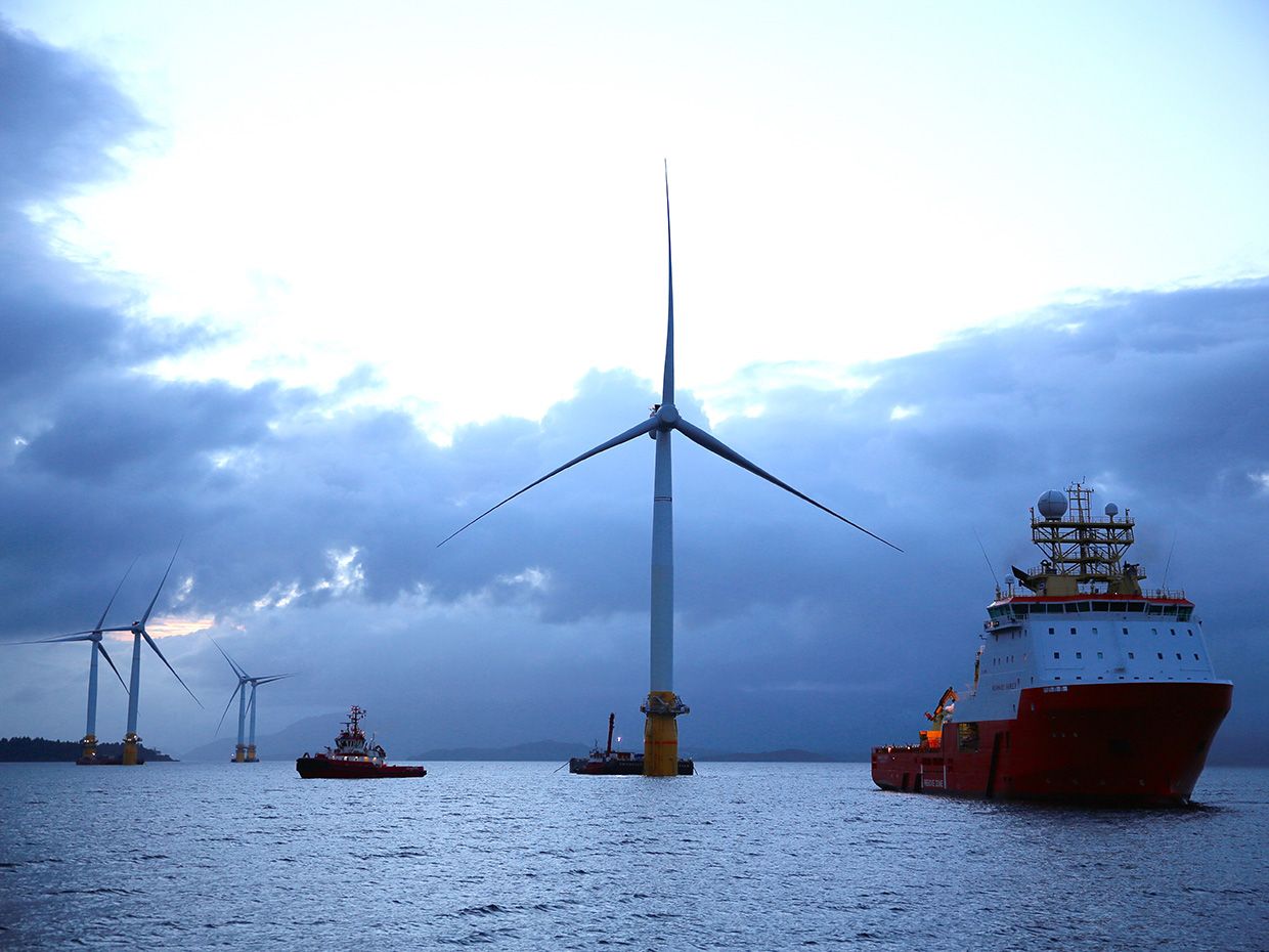 A photo shows several of Statoil's floating wind turbines surrounded by ships at dusk. 