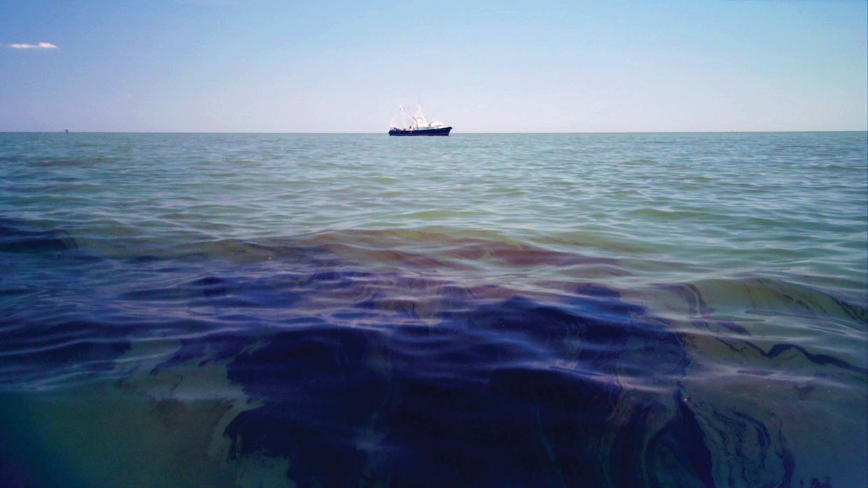 Oil in the water with a tanker on the horizon.