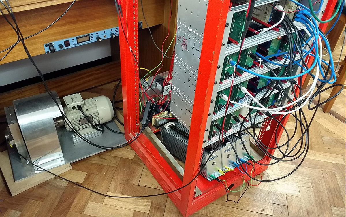 On the left, a beige and silver motor and flywheel equipment. To the right, a large red metal fram cabinet with silver and green component and blue, white and black wires.