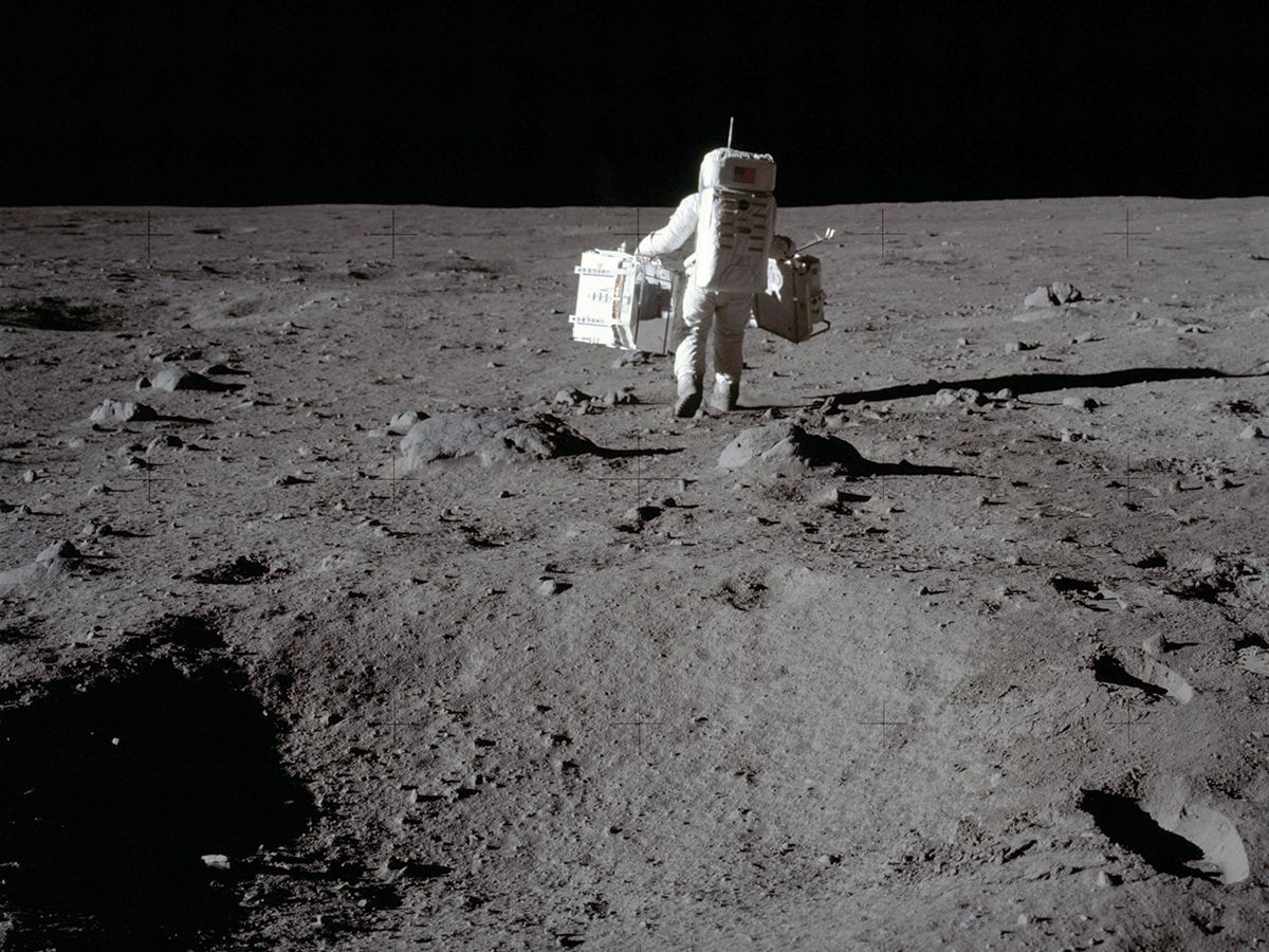 On the moon, Apollo 11 ­astronaut Buzz Aldrin carries research equipment to the deployment area in the Sea of Tranquility.