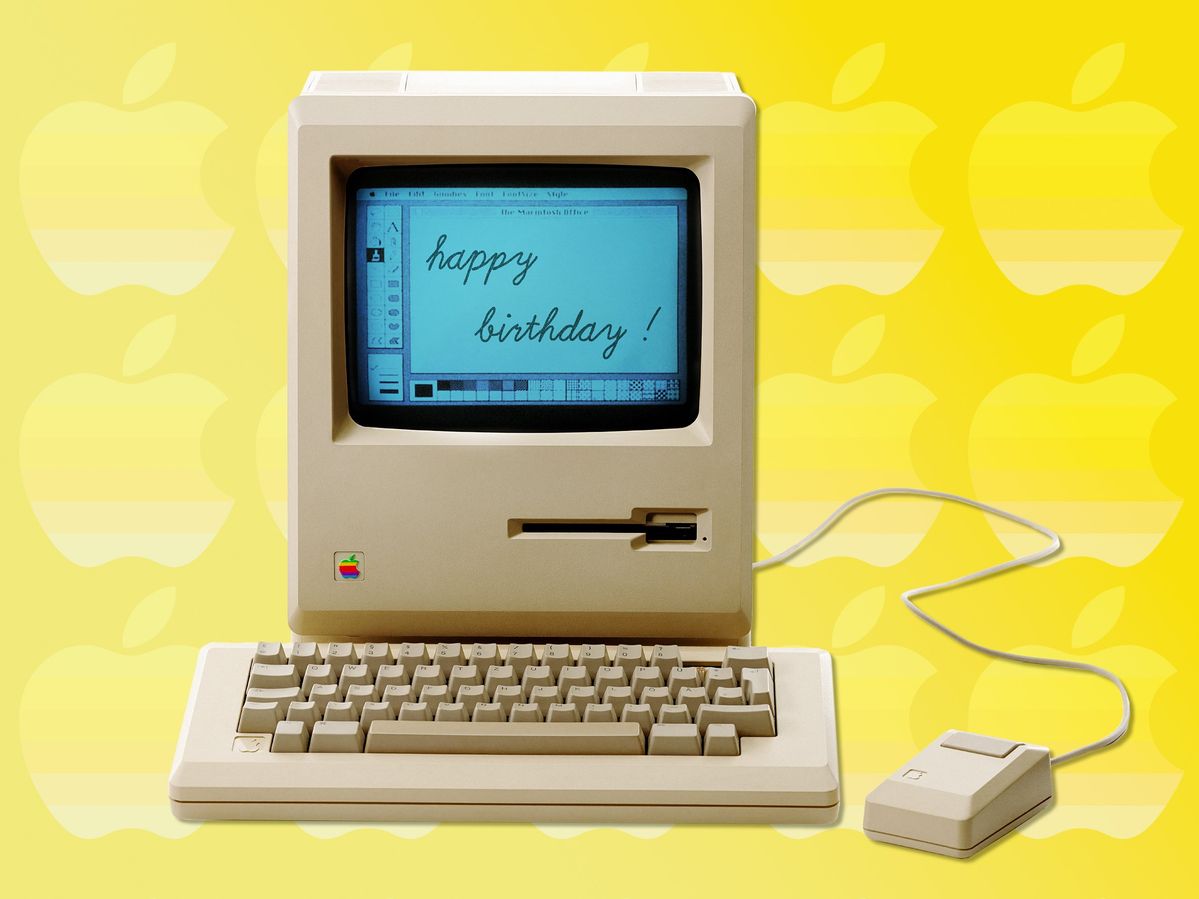 original macintosh computer with keyboard and mouse, screen display says "happy birthday"