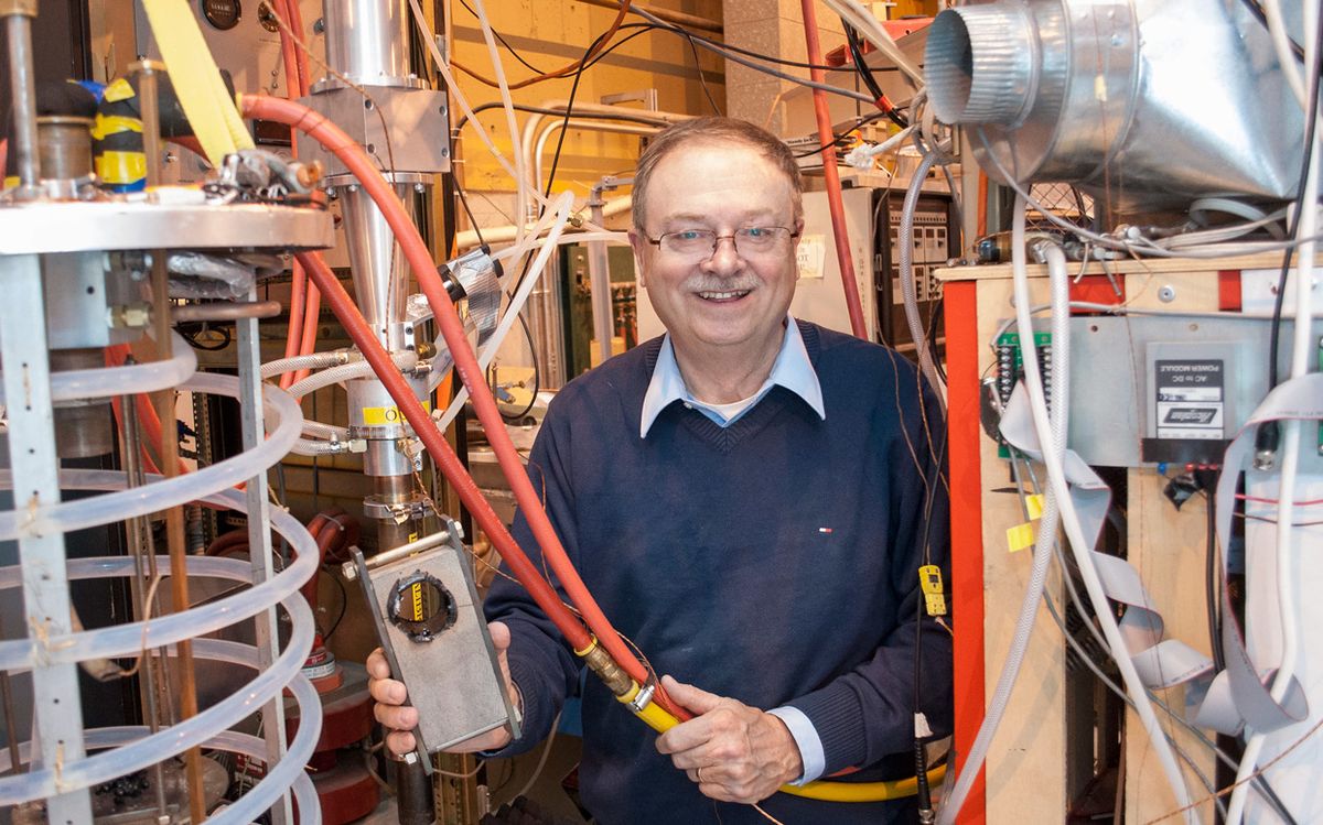 Paul Woskov of MIT holds water-cooling lines leading to a test chamber, and a sample of rock with a hole made by a beam from a gyrotron.